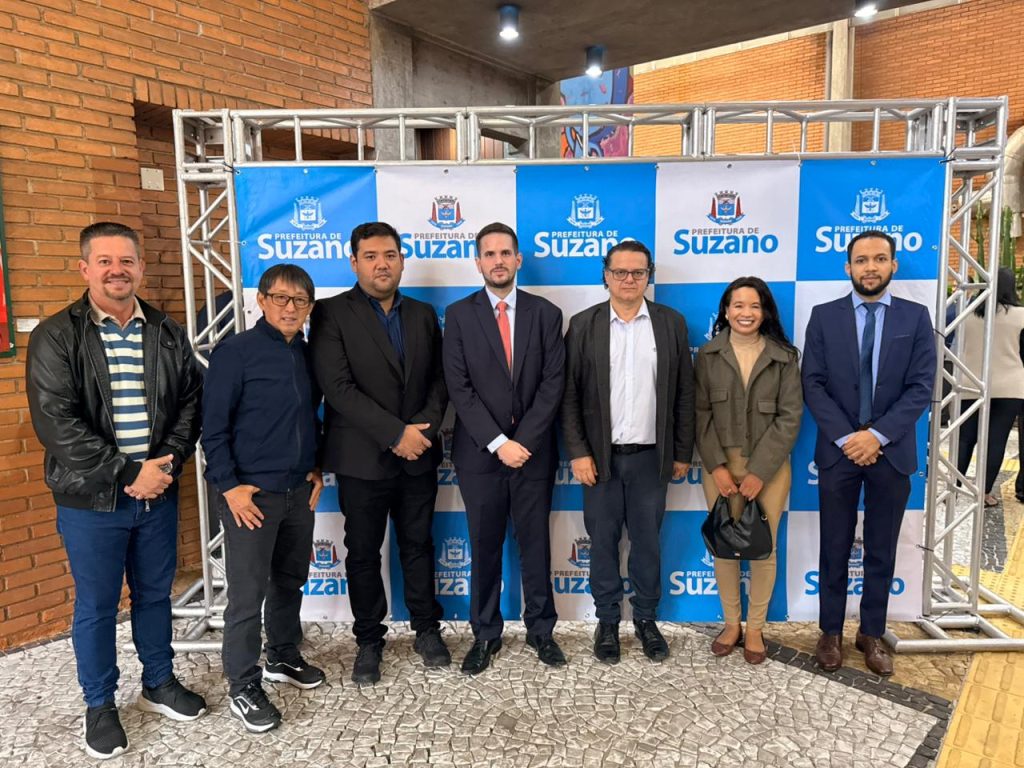 De pé, lado a lado, estão, da esquerda para a direita, vereador Maizena, vereador Artur Takayama, prefeito Pedro Ishi, juiz Heitor Moreira de Oliveira, secretário Geraldo Garippo, representante da Defensoria Pública Cristiane Oliveira e repesentante do Ministério Público Eduardo da Silva.