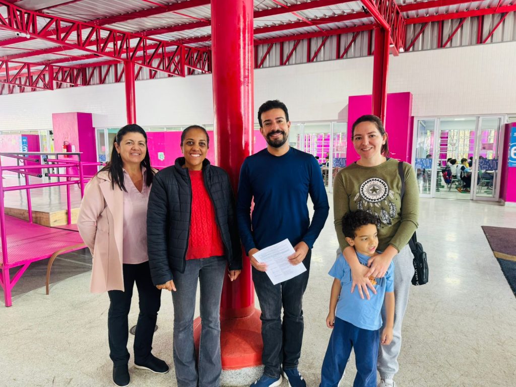 vereador Marcio Malt posa para foto em pátio de escola ao lado de três mulheres e uma criança.