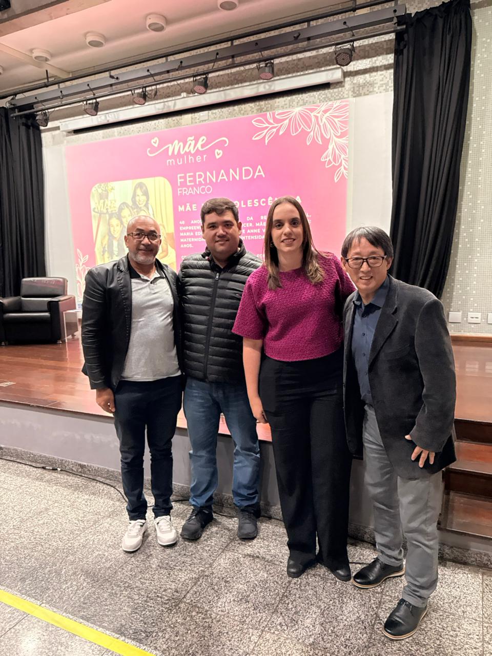 de pé, em frente ao palco do cineteatro, estão, da esquerda para a direita, vereador Josias Mineiro, prefeito Pedro Ishi, primeira-dama Déborah Raffoul Ishi e presidente da Câmara Artur Takayama