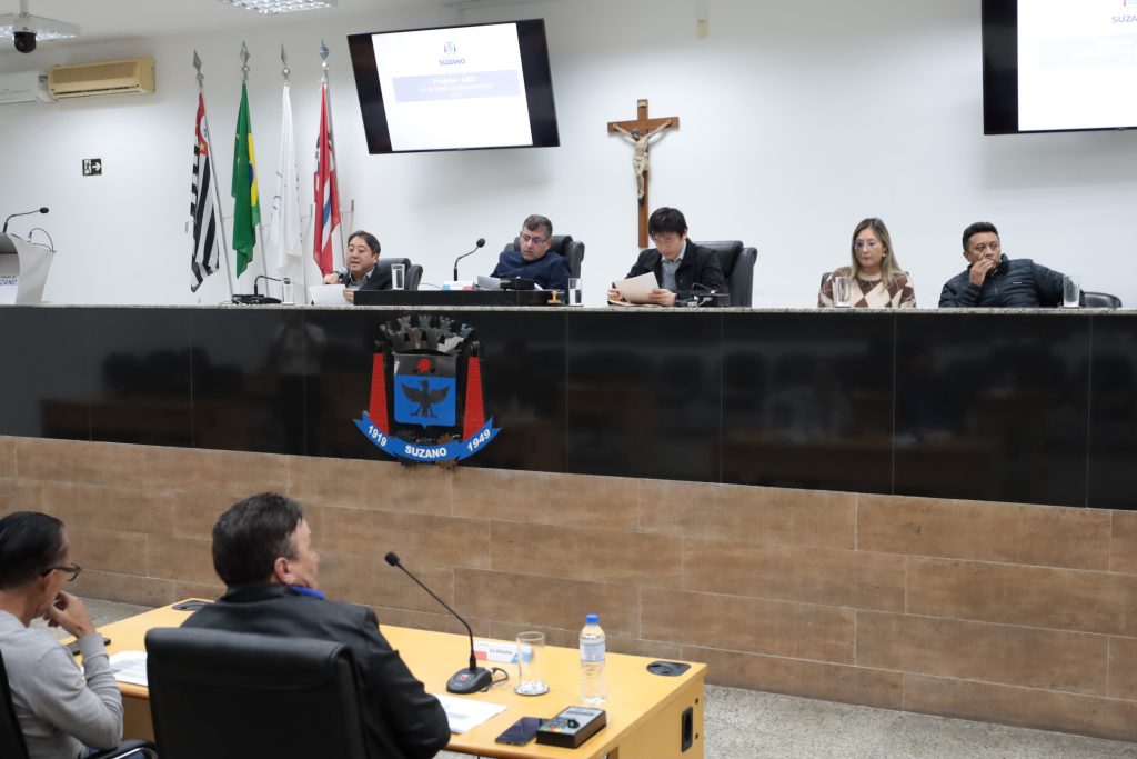 dna Mesa Diretiva da Câmara de Suzano, estão sentados, da esquerda para a direita, o secretário Denis Watanabe, o vereador Denis, o diretor de Orçamento William Nakamura, a assessora estratégica Carolina Umebayashi e o diretor Hélio Cavalcante.