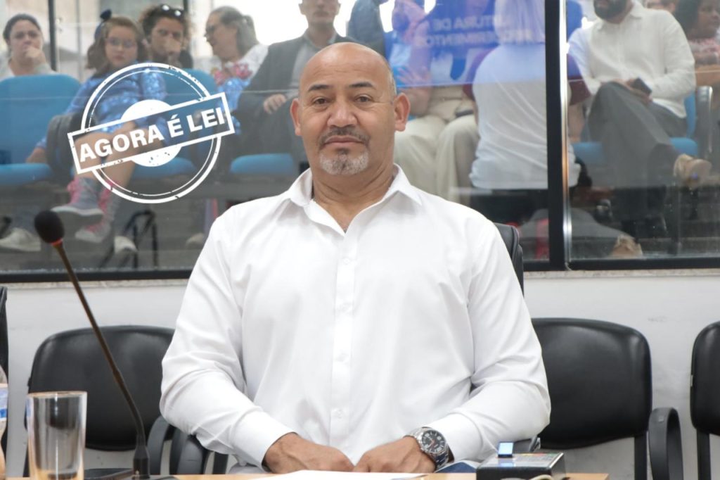 vereador João Sabugo sentado atrás de sua mesa no Plenário. Ele usa camisa social branca.