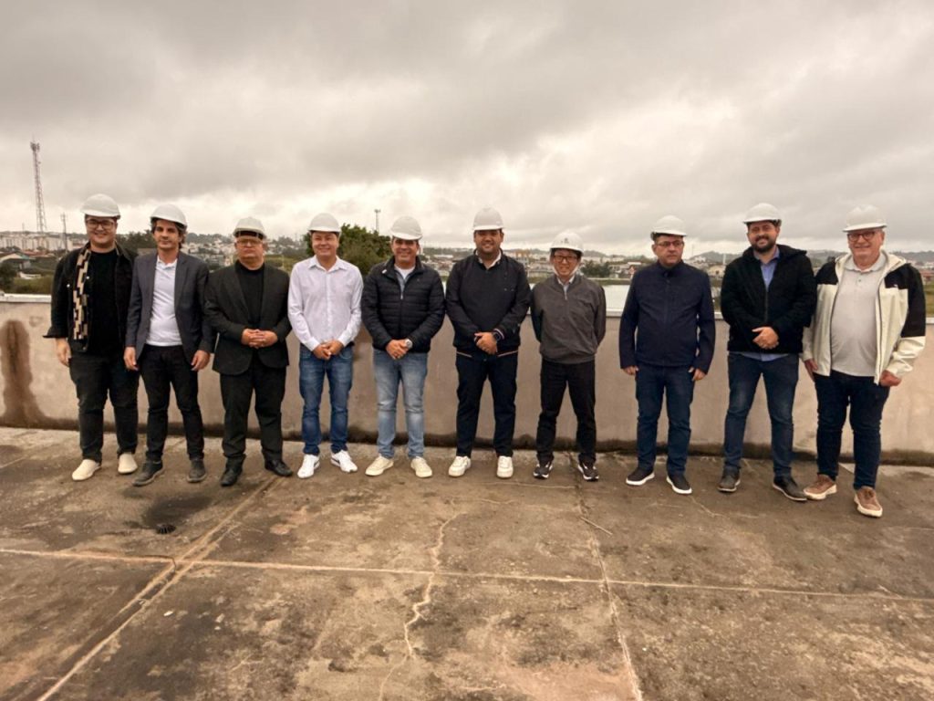 usando capacetes, estão em área externa, da esquerda para a direita, os secretários Paulo Pavione e Alex Santos; os vereadores professor Edirlei, Marcel da ONG e Leandrinho; o prefeito Pedro Ishi; os vereadores Artur Takayama, Denis e André Dourado; e o secretário Samuel de Oliveira.