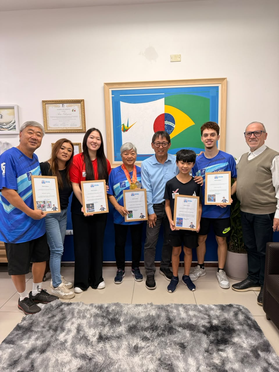  lado a lado, estão na foto, da esquerda para a direita, os atletas Nelson Ueno, Emily Kobayashi e Marlene Takahashi; o vereador Artur Takayama; e o técnico João Mayer e o diretor Julio Mayer.